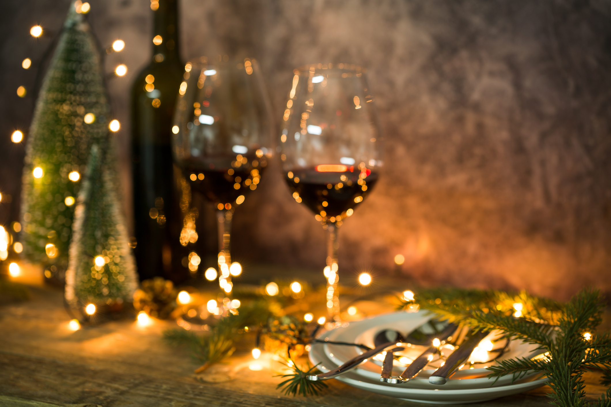 Closeup of red wine on table with Christmas lights. Christmas table and tree.