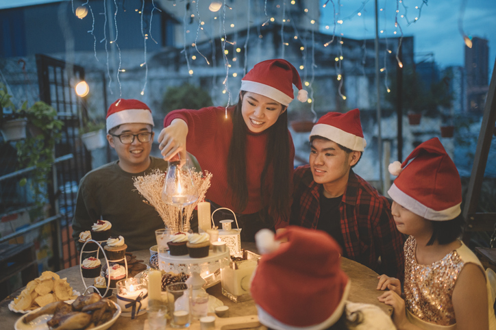 an asian chinese siblings and friends celebrating christmas dinner at front yard of house lighting up candle and setting up table