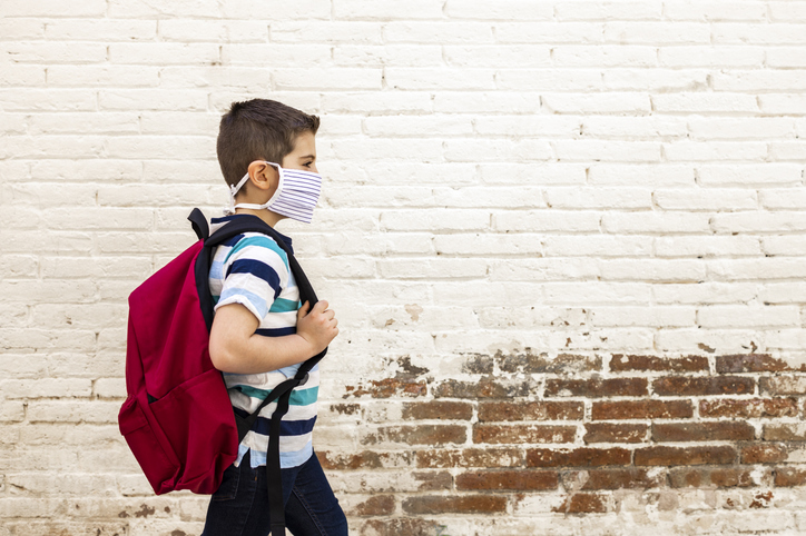 Little boy going to school with protective mask