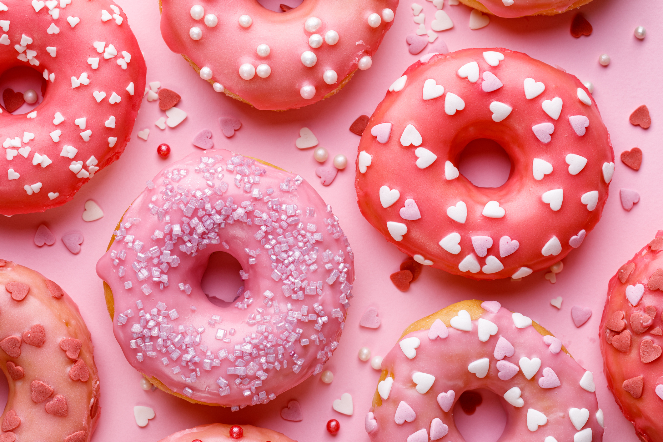 Sweet donuts with pink glaze decorating sprinkles on a pink background