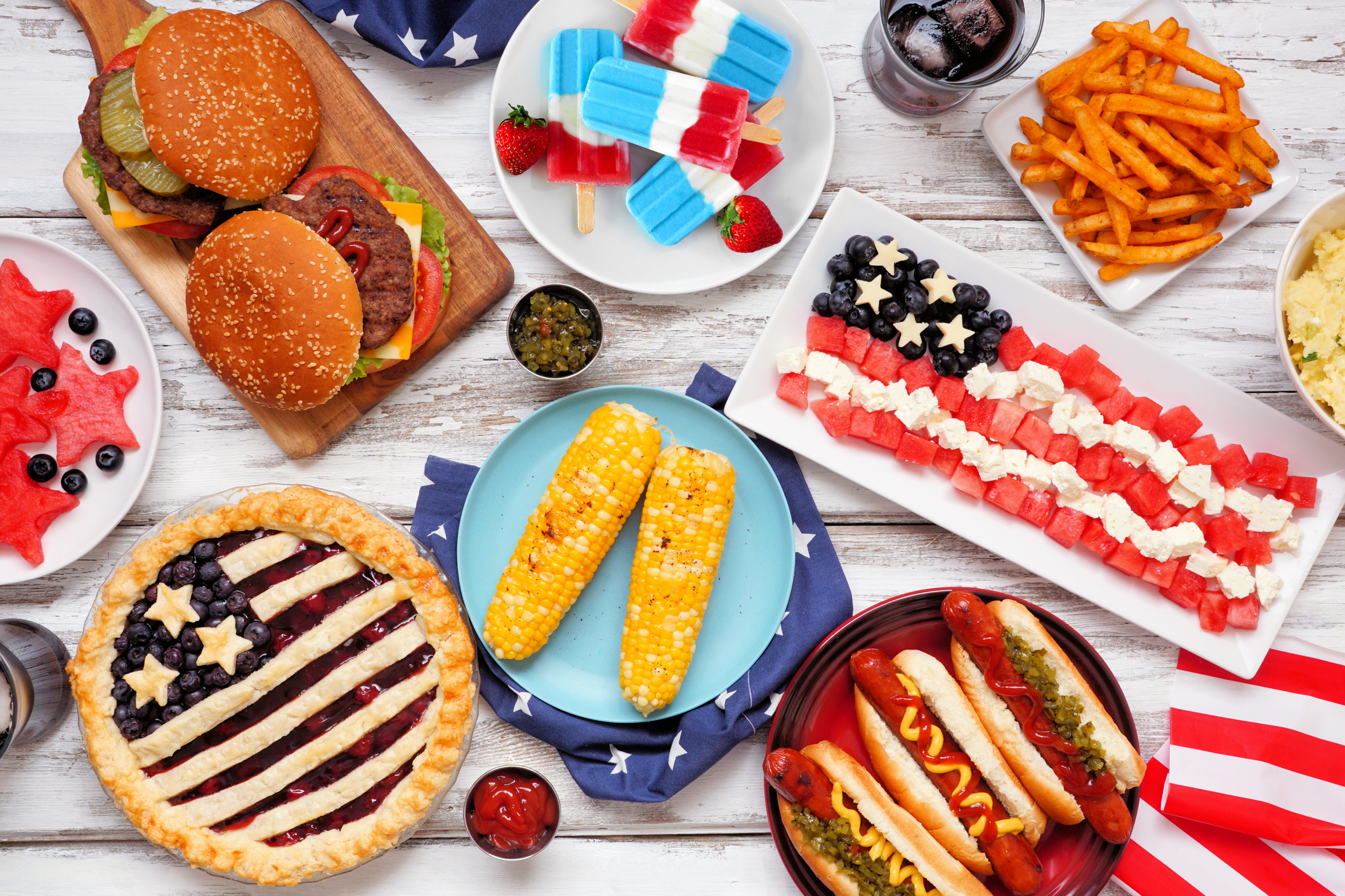 Fourth of July, American food. Above view table scene on white wood.