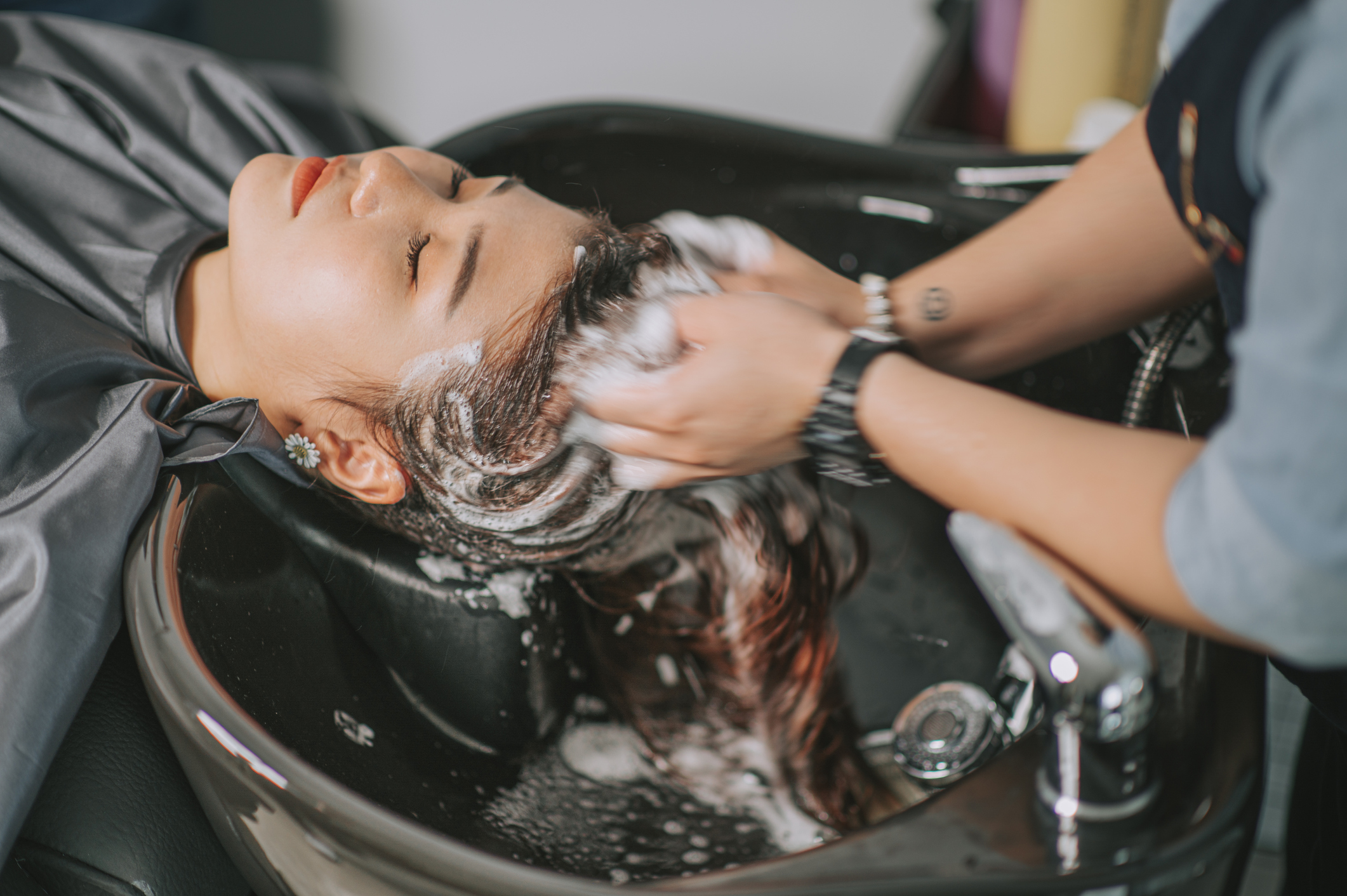 Directly above Asian chinese female lying down for hair wash at hair salon with eyes closed Directly above Asian chinese female lying down for hair wash at hair salon with eyes closed