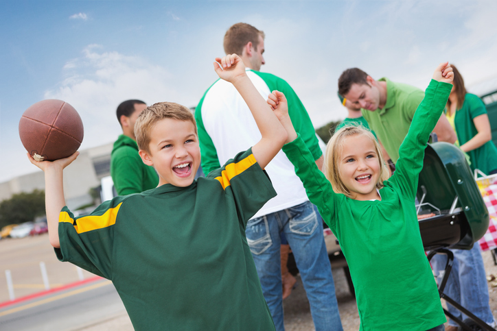 Excited children cheering at tailgate party during college football game