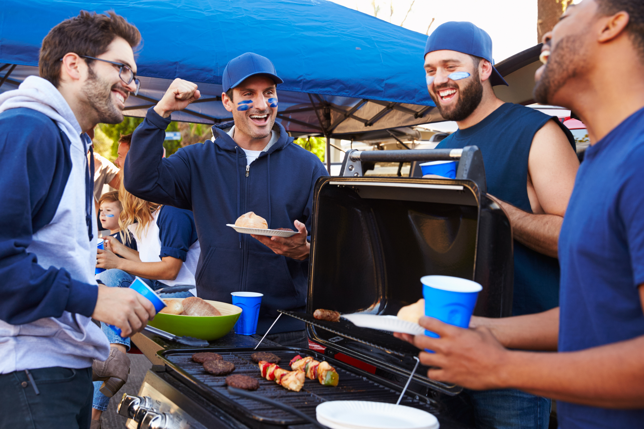 Group Of Male Sports Fans Tailgating In Stadium Car Park