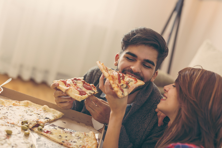 Girl feeding a guy with a pizza slice